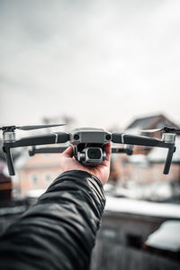 Midsection of man holding camera against sky
