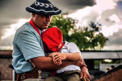 Rear view of man sitting outdoors with his son