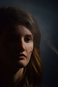 Close-up portrait of a young woman over black background