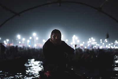 Man and woman standing by illuminated lights at night