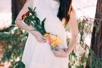 Midsection of bride holding bouquet