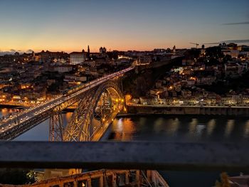 Illuminated bridge over river in city against sky at night