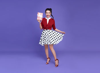 Full length portrait of woman standing against blue background