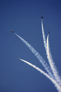 Low angle view of airshow against clear blue sky