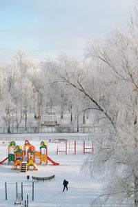 Bare trees on snow covered field against sky