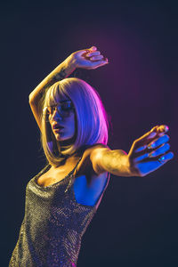 Woman in dress dancing against black background