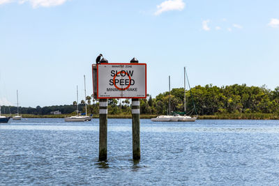 Information sign by river against sky