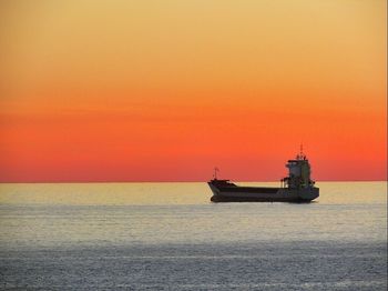 Boat sailing in sea at sunset