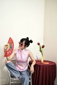 Woman sitting on potted plant against wall