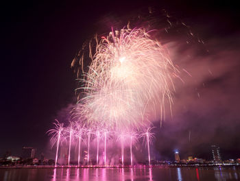 Firework display over river against sky at night