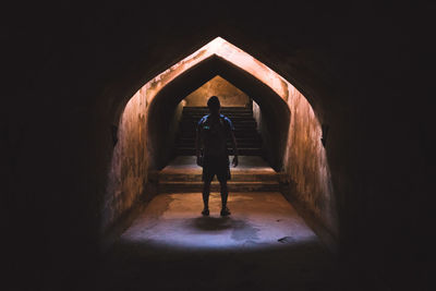 Rear view of man standing in dark tunnel