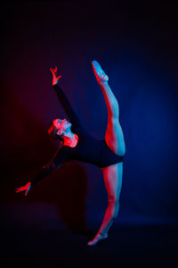 Low section of woman with arms raised against black background