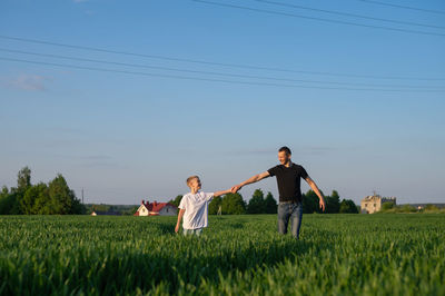 Rear view of woman standing on field against clear sky