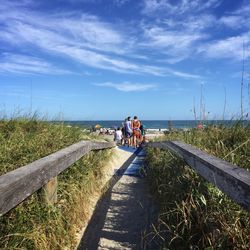 People walking towards beach against sky