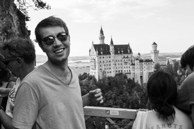 Portrait of young man wearing sunglasses standing on observation point against sky