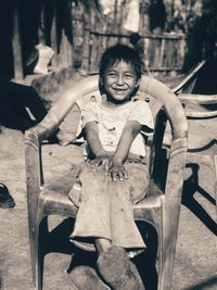 Smiling girl sitting on chair outdoors