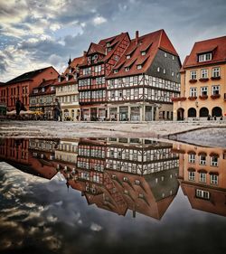 Reflection of buildings in canal against sky