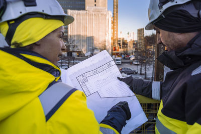 Two engineers looking at blueprints at construction site