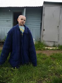 Portrait of boy wearing large jacket while standing on field