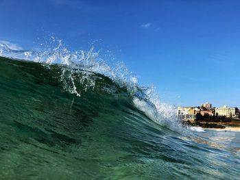 Water splashing in sea against blue sky