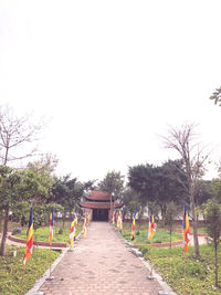 Rear view of people walking on footpath in park against clear sky