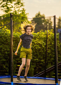 Full length of young woman standing against trees