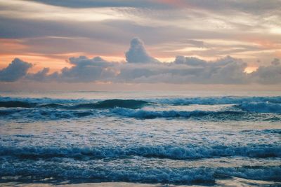 Sea waves against cloudy sky during sunset