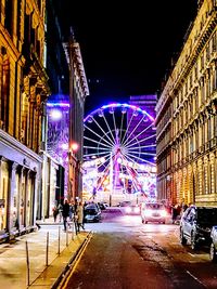 People at illuminated city against sky at night