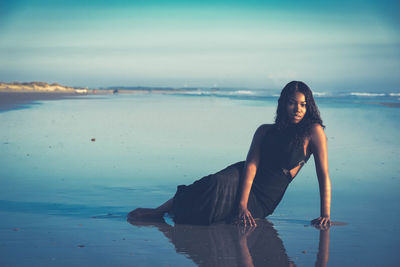 Portrait of woman standing on beach against sky