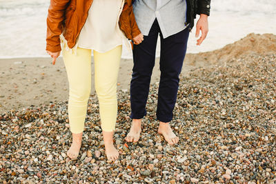 Low section of couple standing on beach