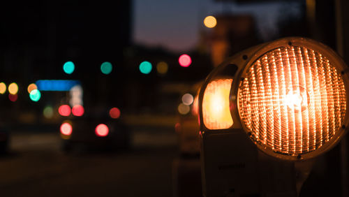 Close-up of illuminated lighting equipment on street at night