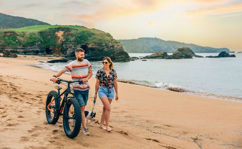 Couple with a fat bike taking a walk on the beach