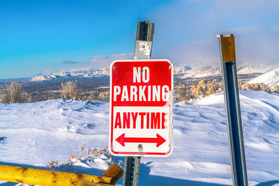 Information sign on snowcapped mountain against sky