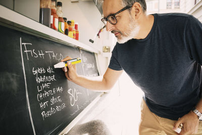 Close-up of vendor writing menu on blackboard at food truck