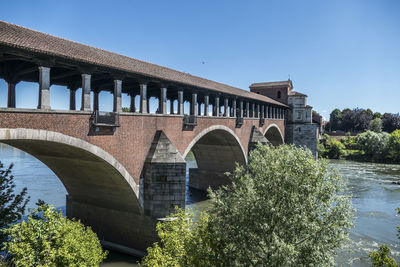 Covered bridge in red brick in pavia over the ticino river