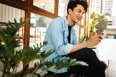 Young man looking away while sitting on wall