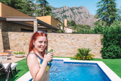 Portrait of woman holding drink by pool