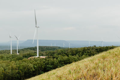 Wind turbines on field against sky