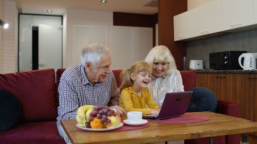 Grandparent with granddaughter using laptop at home