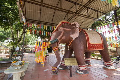 Elephant sculpture on tiled floor against trees