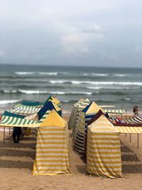 Rear view of umbrellas on beach against sky