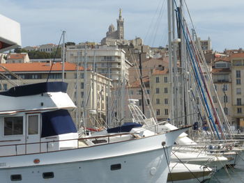 Boats moored at harbor against sky in city