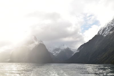 Scenic view of sea by mountains against sky