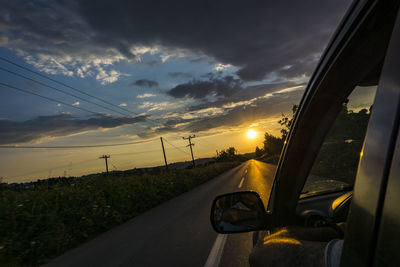 Car on road against sky at sunset