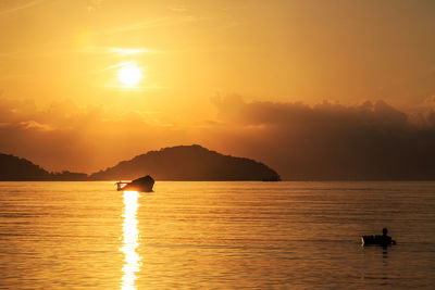 Silhouette boat in sea against sky during sunset