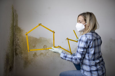 Portrait of young woman standing against wall