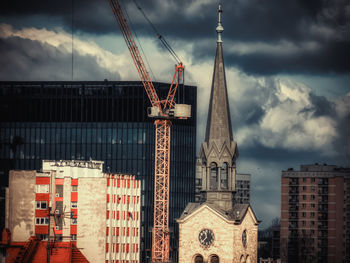 Crane by building against sky in city