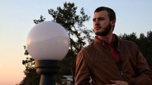 Portrait of young man looking away against sky