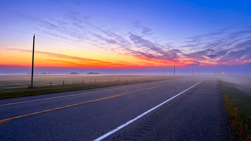 Empty road against sky during sunset