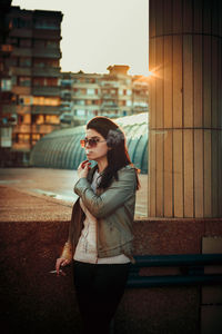 Young woman smoking while standing on street in city